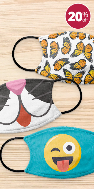 3 Custom designed face masks on a wooden table. One has a monarch butterfly print pattern, one is a cartoonish cat face, and one is a teal mask with the winking tongue out emoji.