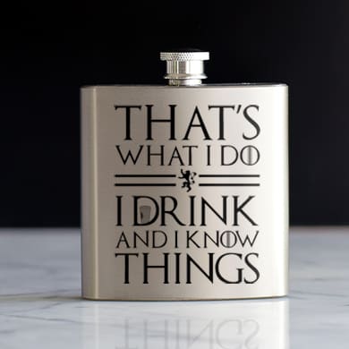 A silver drinking flask with an official licensed Game of Thrones design showing stylized text that reads: That's What I Do. I Drink and I Know Things.