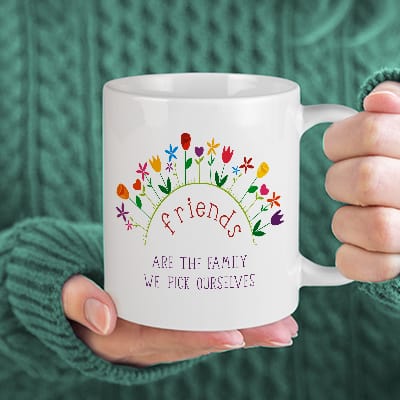 Custom coffee mug with a Spring design showing flowers and stylized text that reads: Friends are the family we pick ourselves.