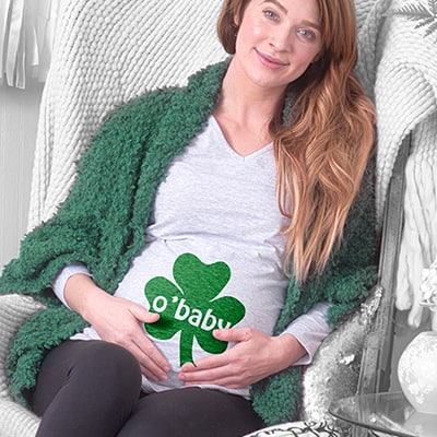 A pregnant woman wearing a maternity tee with a design reading - O'Baby