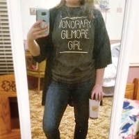 Female wearing an Honoray Gilmore Girl shirt holding a stainless steel travel mug with a Luke's Diner design