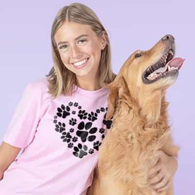 Young woman and her dog. The woman is wearing a pink custom printed t-shirt with a heart design made from paw prints.