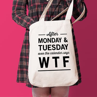 Woman holding tote bag with stylized text custom design that reads: After Monday and Tuesday, even the calendar reads WTF.