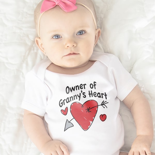 A cute baby wearing a baby bodysuit with a design reading - Owner of Granny's Heart.