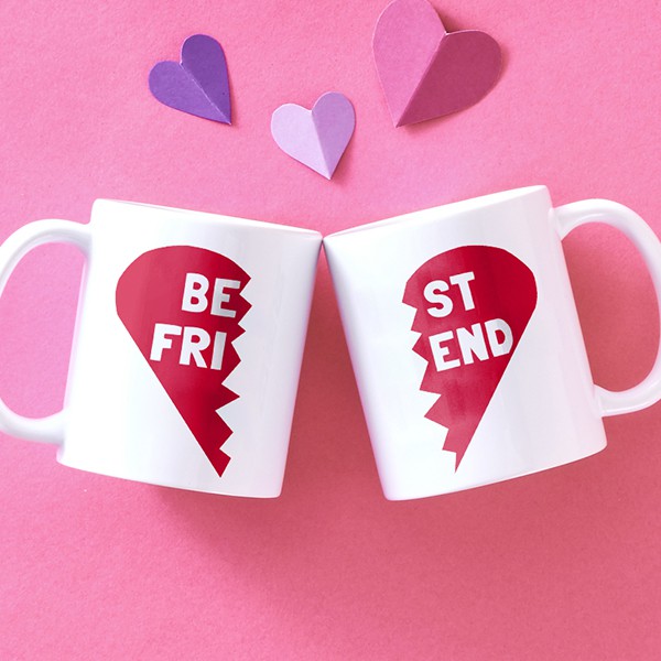 2 standard mugs side by side. They each have one half of a heart and the words Best Friend split between the two