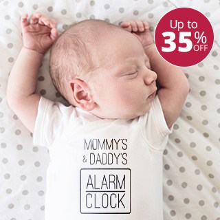 Baby asleep wearing baby bodysuit with stylized text design that reads: Mommy and Daddy's Alarm Clock