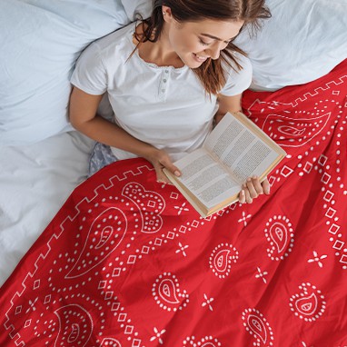 Woman eading in bed covered by a custom design paisley pattern duvet cover.