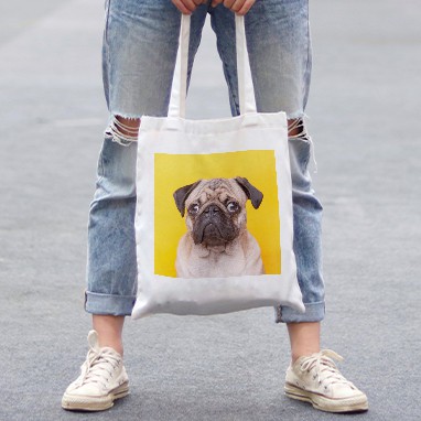 Woman holding a tote bag with a cute custom photo design of a pug.