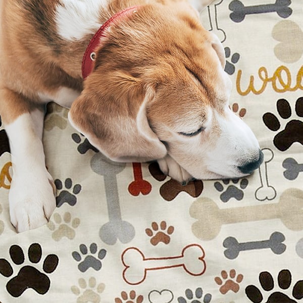 Cute puppy laying on a blanket with a dog bone and paw print design pattern.