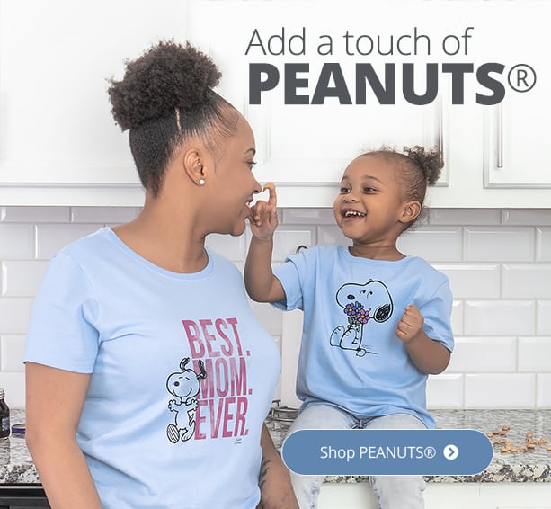 African American mother and daughter sitting in the kitching wearing shirts with officially licensed PEANUTS® designs. The mom's says - Best Mom Ever. While the daughter's is a drawing of Snoopy(TM) holding flowers.