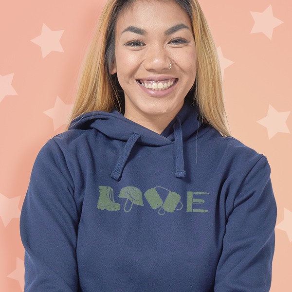 A female wearing a hoodie with a design that reads - Love. Love is spelled with a boot for the L, a helmet for the O, and dog tags for the V - signifying military appreciation.