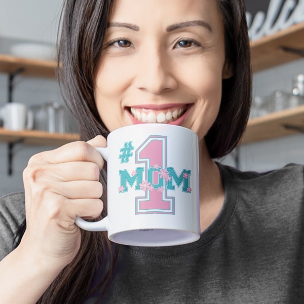 A closeup shot of a mom drinking coffee from her mug with a design reading - #1 Mom.