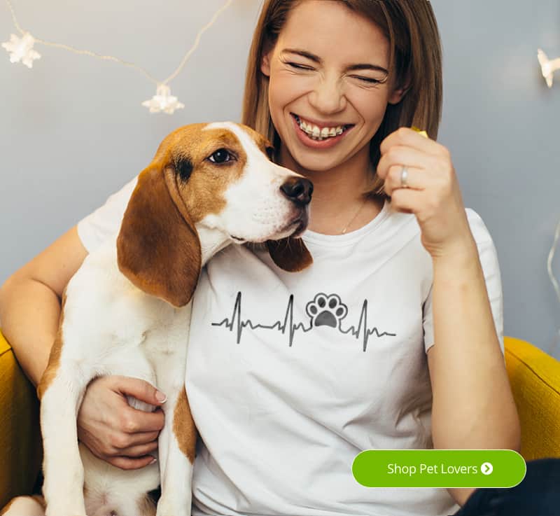 Female sitting with her dog laughing while wearing a shirt that looks like a heart monitor graph with a puppy paw print.