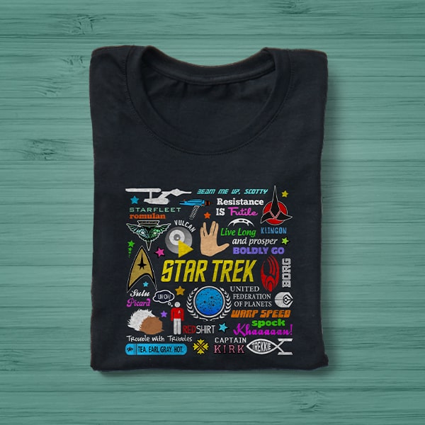 A black t-shirt with a Star Trek design laying on a green table.