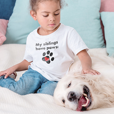 Adorable dog being pet by a little girl wearing a custom printed shirt.