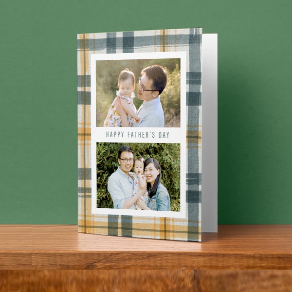 A Father's Day Card sitting on a table with custom photos of a father and his child and a family photo. Text in between the photos reads Happy Father's Day.