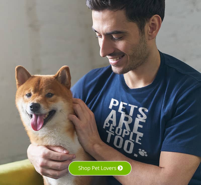 A male sitting with his dog wearing a blue t-shirt with a design that reads Pets are People Too.