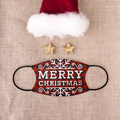 A custom printed face mask from CafePress displaying a Merry Christmas festive design laid out with a Santa hat.