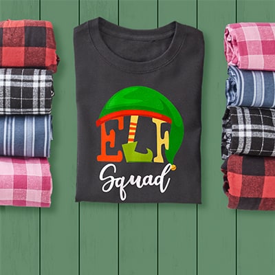 Elf Squad design on custom printed CafePress pajamas laying on a festive green wooden table.