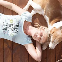 Woman laying on the ground happily in her custom Cafepress T-shirt while her dog lies with her