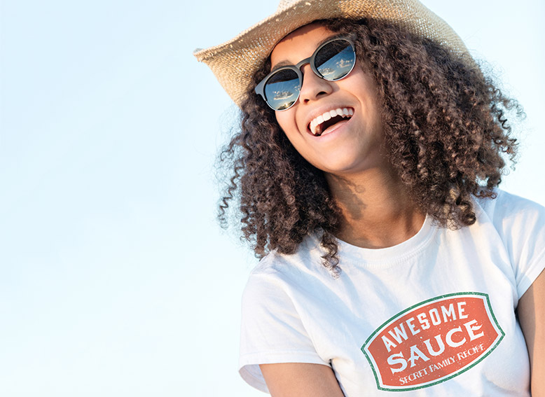 Girl in a Straw Hat and Sunglasses, smiling wearing a classic t-shirt with an Awesome Sauce design