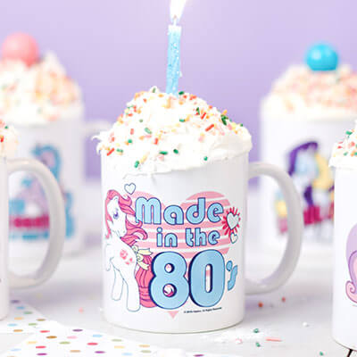 Need a special birthay gift idea? Find the perfect gift with our custom designs, personalized design, add your own photo designs printed on apparel, t-shirts, mugs, drinkware, blankets, hats, scarves, and more. Image of a set of My Little Pony birthday mugs with personalized names and a cupcake baked inside.