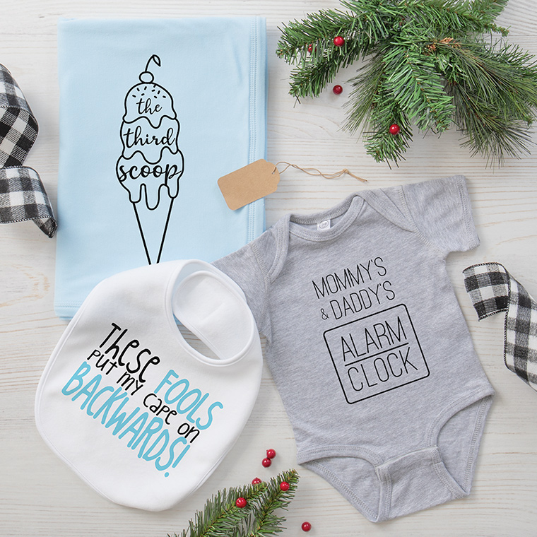 Baby gift ideas featuring grey baby bodysuit with Mommy and Daddy's Alarm Clock design, baby bib with These Fools Put My Cape On Backwards design, and blue baby blanket with The Third Scoop design.