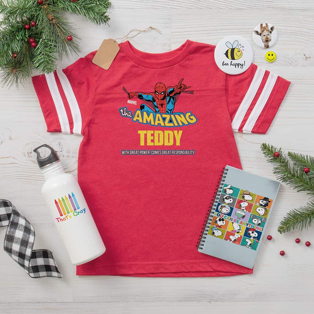 Kid's gift ideas featuring red football t-shirt with Run Kick Score design, water bottle with That's Cray design, notebook with monogrammed design, and buttons with cute animal designs.