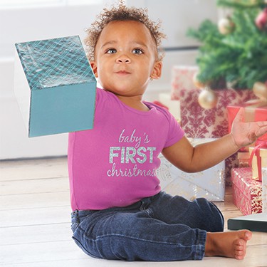 Baby playing with gift boxes wearing raspberry baby onesie with text design that reads: Babies first Christmas.