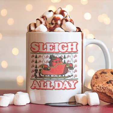 Mug filled with hot cocoa and marshmallows with ugly Christmas sweater design that reads: Sleigh All Day.